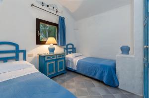 Residence I Cormorani Alti في بايا سردينيا: غرفة نوم بسريرين وطاولة بها مصباح