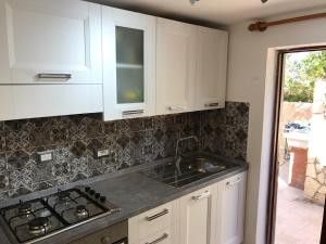 a kitchen with white cabinets and a sink at Casa Bianca Rais Gerbi in Finale