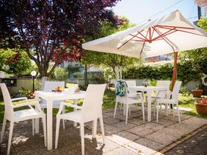 un tavolo e sedie bianchi e un ombrellone di Minturnae Hotel a Scauri