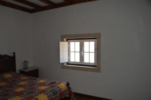 Schlafzimmer mit einem Bett und einem Fenster in der Unterkunft Casinha da Avó Maria in Alcobaça