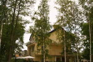 a yellow house with trees in front of it at Pokoje Gościnne Akwatel in Jastarnia