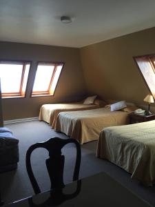 Un dormitorio con 2 camas y una silla. en Hotel Apart Colón en Puerto Montt