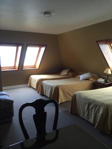 a bedroom with two beds and a chair in it at Hotel Apart Colón in Puerto Montt