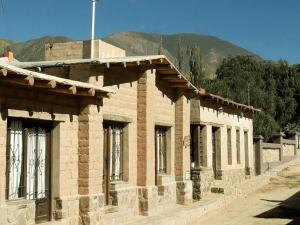 an old brick building with a mountain in the background at Hosteria La Pushka in Purmamarca