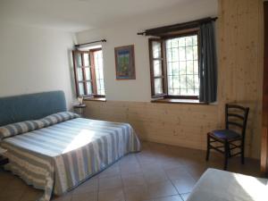 a bedroom with a bed and a chair and windows at Agriturismo Affittacamere Barbarossa in Dogliani