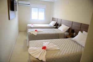 a room with two beds with red bows on them at Pousada Recanto do Mar in Navegantes