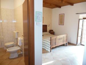 a bathroom with a bed and a toilet in a room at Agriturismo Affittacamere Barbarossa in Dogliani