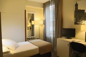 a hotel room with a bed and a desk with a television at Gran Hotel España in Oviedo