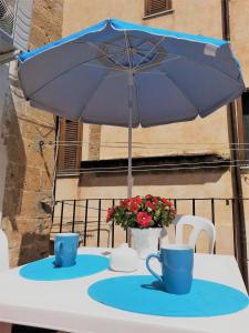 un tavolo con un ombrello blu e due tazze sopra di La Bifora a Sciacca