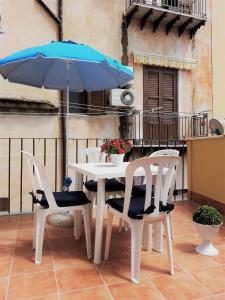 un tavolo con sedie e un ombrellone su un balcone di La Bifora a Sciacca
