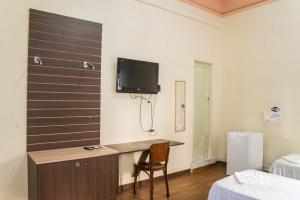 a room with a desk and a tv on the wall at Hotel Palácio - Próx ao Hospital Santa Casa in Porto Alegre