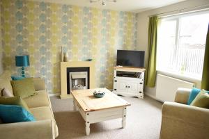 a living room with a couch and a table and a tv at 103 Bewick Serviced Accommodation in Newton Aycliffe