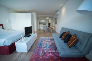 sala de estar con sofá azul y TV en Bracara Guest House "São Bento" - "Palácio do Raio", en Braga