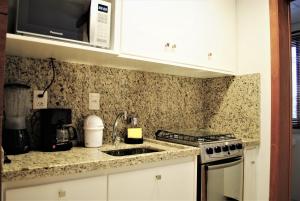 eine Küche mit weißen Schränken und einer Arbeitsplatte in der Unterkunft Apartamento Moderno Centro Gramado in Gramado