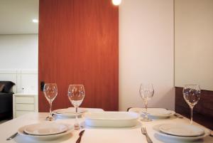 einen Tisch mit drei Weingläsern und Tellern darauf in der Unterkunft Apartamento Moderno Centro Gramado in Gramado