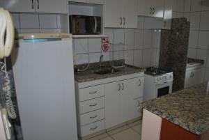 cocina con armarios blancos y nevera blanca en Thermas dos Bandeirantes - 3 Quartos - Achei Férias, en Caldas Novas