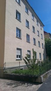 un grand bâtiment avec une clôture devant lui dans l'établissement Apartment Avenzio, à Wurtzbourg