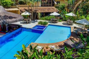 a pool with chairs and umbrellas next to a resort at Pousada Pedra Torta in Itacaré