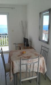 a dining room with a table and chairs and a window at Apartmani Jelena in Podgora