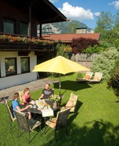a man and two children sitting at a table under an umbrella at Appartement Rofan in Pertisau