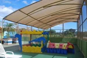una zona de juegos con una zona de juegos con una sombrilla grande en Prive das Thermas I - 3 Quartos - Achei Ferias, en Caldas Novas