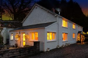 uma casa branca com janelas iluminadas à noite em 1 Tan Yr Eglwys Barn Cottage em Pontardawe