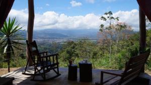 two chairs sitting on a porch with a view at Hacienda Monteclaro in Turrialba