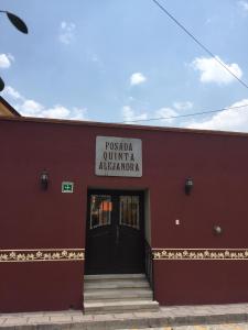 um edifício vermelho com um sinal que lê pueblo quillian albuquerque em Posada Quinta Alejandra em Bernal