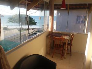a room with a table and chairs and a view of the ocean at Residencial Samuel in Bombinhas