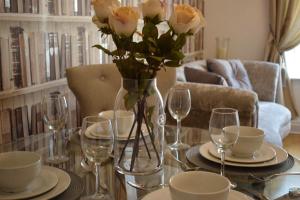 una mesa con un jarrón de rosas. en Luxury 2 bed Apartment en Witney