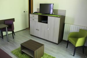 a living room with a tv and a table and chairs at Hotel Stanger in Lovran
