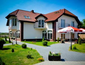 a large house with a garden and an umbrella at Rezydencja Lux in Rewa