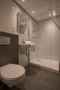 a bathroom with a toilet and a sink and a tub at Hotel Eperland in Epen