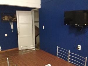 Habitación con pared azul, TV y puerta. en Apartamento en el centro de mercedes URUGUAY, en Mercedes