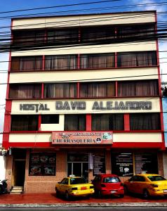 dos coches estacionados frente a un edificio en Hostal David Alejandro, en Quito