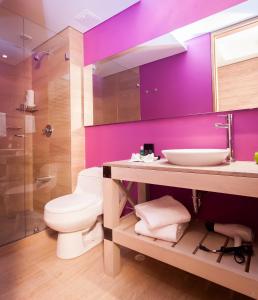 
a bathroom with a toilet a sink and a mirror at Mika Suites in Bogotá
