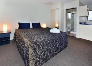 a bedroom with a large bed with blue pillows at Arena Motel in Christchurch