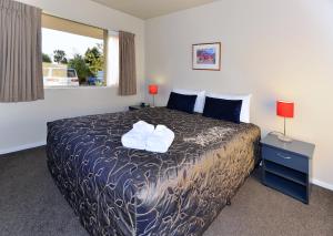 een slaapkamer met een bed en een raam bij Arena Motel in Christchurch