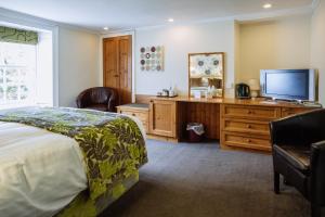 a bedroom with a bed and a flat screen tv at Selkirk Arms Hotel in Kirkcudbright