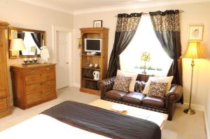 a bedroom with a bed and a couch and a tv at The Globe Inn in Chagford