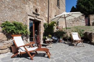 2 sedie e un ombrellone su un patio in pietra di Vinto House Civita a Bagnoregio