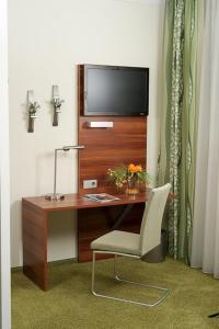 einen Schreibtisch mit einem TV und einem Stuhl in einem Zimmer in der Unterkunft Hotel und Cafe Paso in Vierkirchen