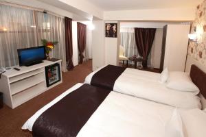 a hotel room with two beds and a flat screen tv at West Plaza Hotel in Bucharest
