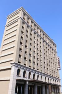 a tall white building with a blue sky in the background at Fushin Hotel - Tainan in Tainan