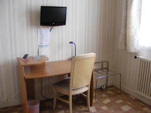 a desk with a chair and a television on a wall at Hotel du Commerce in Challans