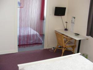 a room with a desk and a bed and a desk with a computer at Hotel du Commerce in Challans