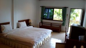 a bedroom with a bed and a tv and a window at Baan Pitcha บ้านพิชชา in Lamai