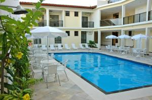 uma piscina com cadeiras e guarda-sóis ao lado de um hotel em San Manuel Praia Hotel em Aracaju