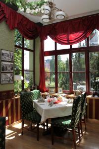 een eetkamer met een tafel, stoelen en ramen bij Willa West Ende in Szczecin