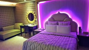 a purple bedroom with a bed and a chair and a table at Full Moon Boutique Motel in Hsinchu City